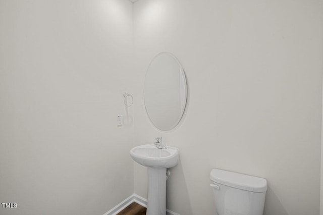 bathroom featuring toilet, baseboards, and wood finished floors