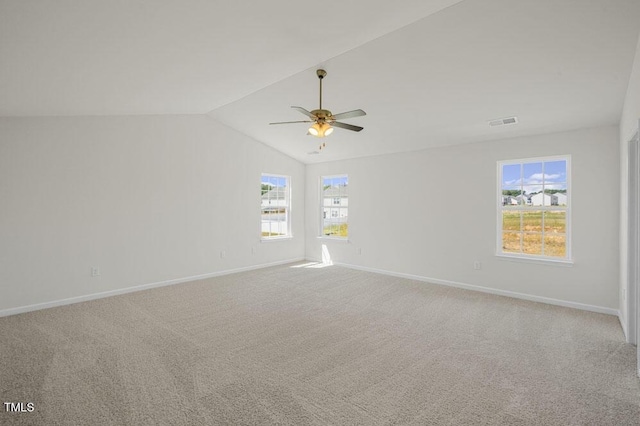 empty room featuring a healthy amount of sunlight, baseboards, visible vents, and lofted ceiling