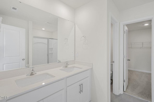 full bathroom with double vanity, a stall shower, a sink, and visible vents