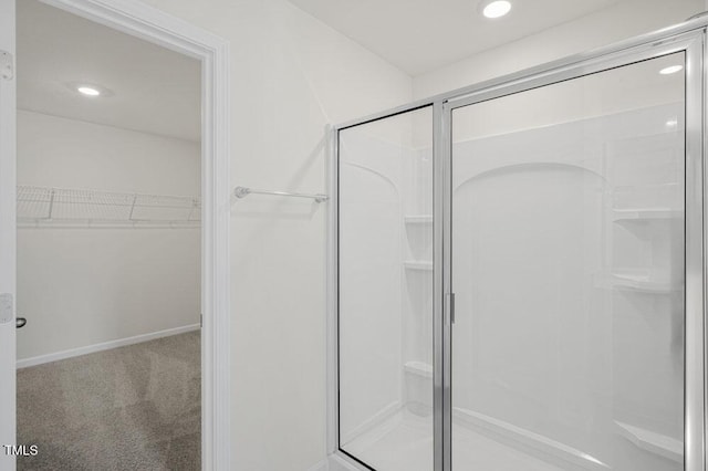 full bathroom with a stall shower, a spacious closet, baseboards, and recessed lighting