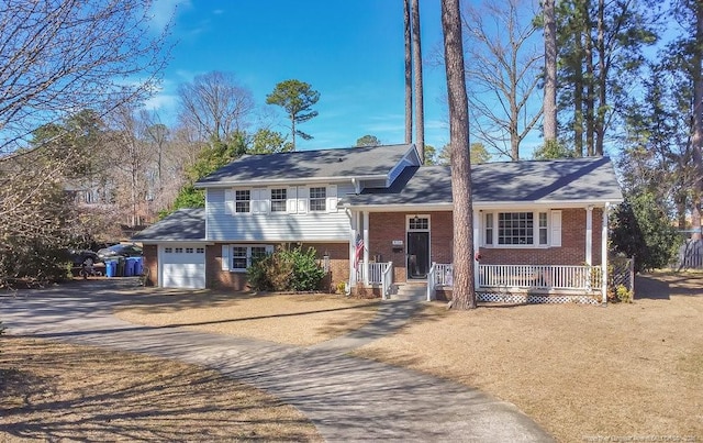 tri-level home featuring driveway, a garage, a porch, and brick siding