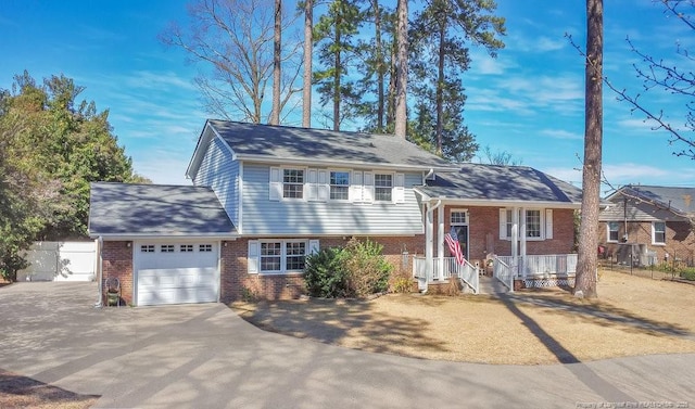 tri-level home with brick siding, an attached garage, fence, and aphalt driveway