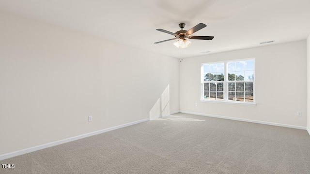 carpeted spare room featuring a ceiling fan, visible vents, and baseboards