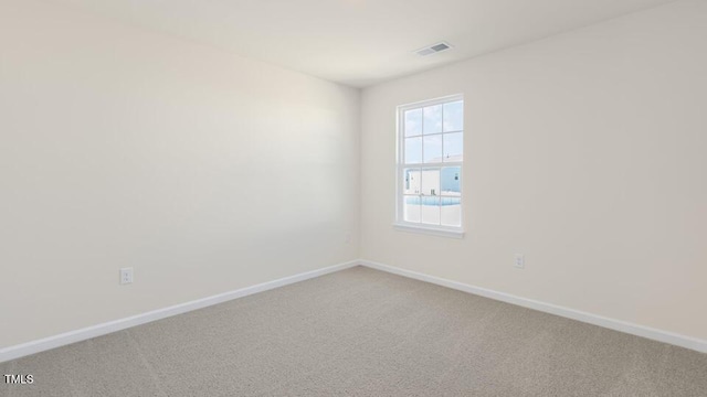 empty room featuring light carpet, visible vents, and baseboards