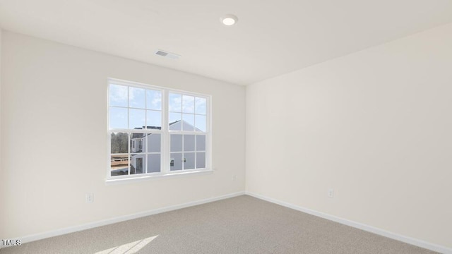 carpeted spare room featuring visible vents and baseboards