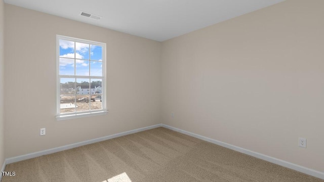 spare room with baseboards, visible vents, and light colored carpet