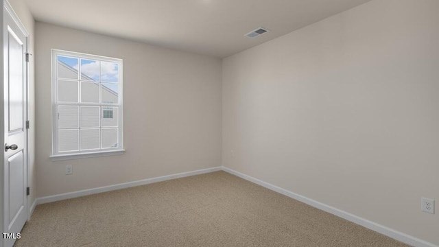 spare room with baseboards, visible vents, and light colored carpet