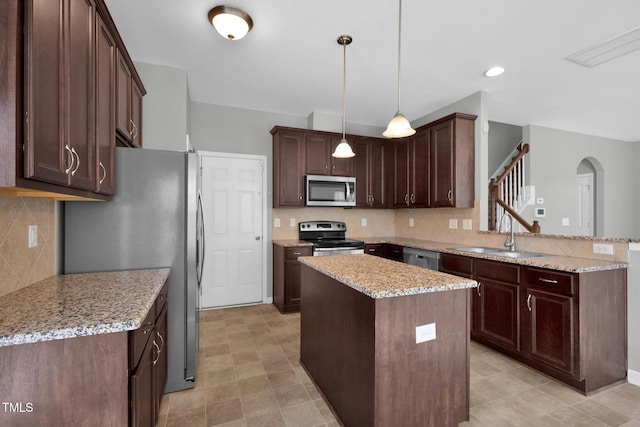 kitchen featuring visible vents, a center island, a peninsula, stainless steel appliances, and a sink