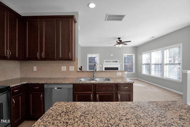 kitchen featuring visible vents, dishwasher, light stone counters, a fireplace, and a sink