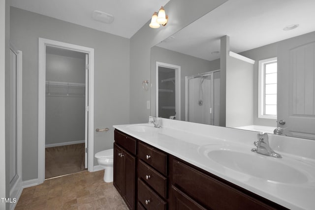 bathroom with baseboards, double vanity, a sink, and a shower stall