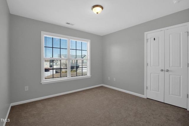 unfurnished bedroom featuring visible vents, baseboards, a closet, and carpet flooring