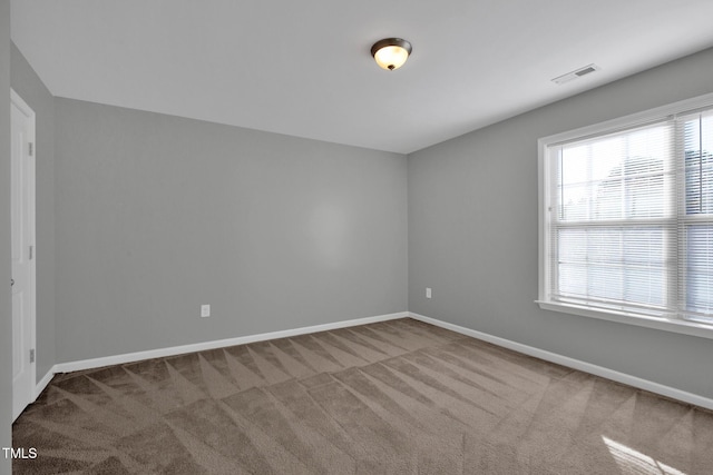 unfurnished room with carpet flooring, visible vents, and baseboards