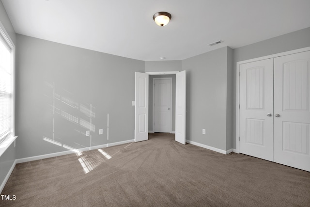 unfurnished bedroom featuring a closet, carpet flooring, visible vents, and baseboards