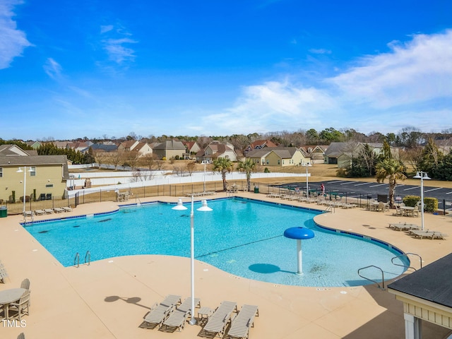 community pool featuring a patio, fence, and a residential view