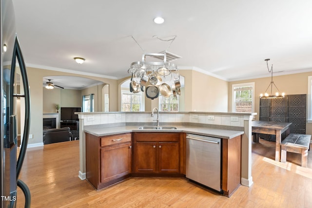 kitchen featuring brown cabinets, refrigerator, light countertops, stainless steel dishwasher, and a sink