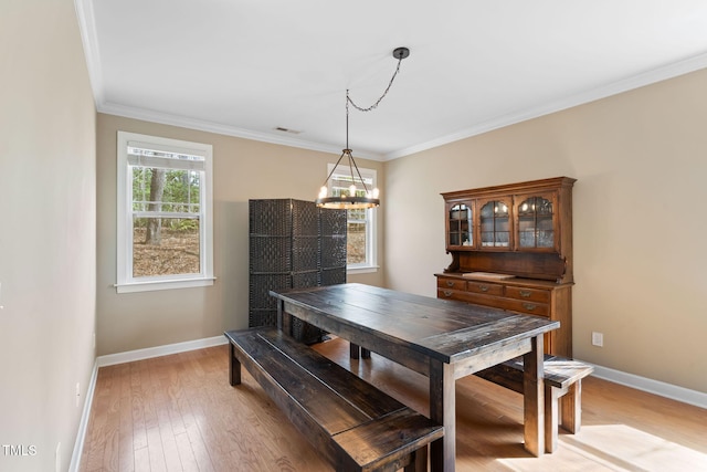 dining space with ornamental molding, light wood finished floors, visible vents, and baseboards