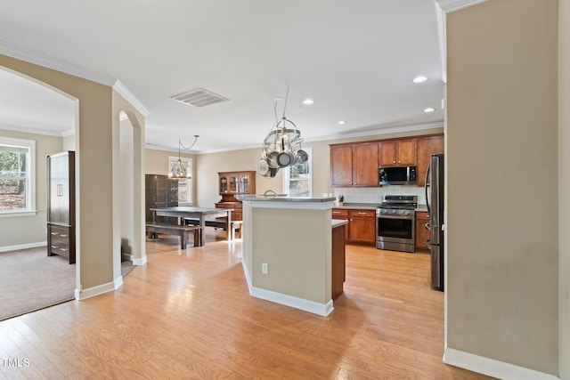 kitchen featuring arched walkways, visible vents, decorative backsplash, appliances with stainless steel finishes, and light wood-type flooring