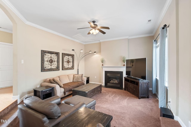 living area featuring a ceiling fan, carpet, ornamental molding, and arched walkways