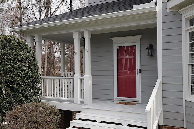 doorway to property featuring a shingled roof and a porch