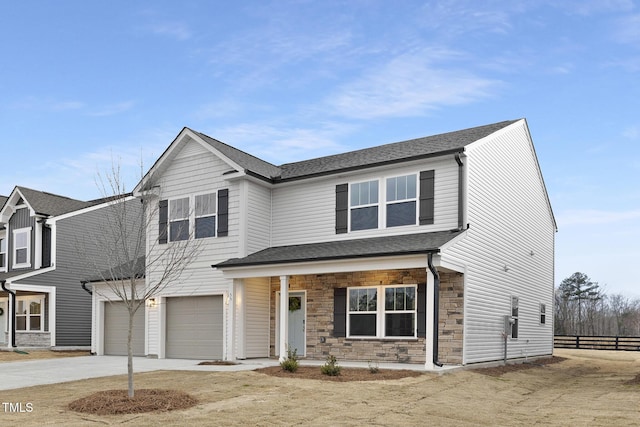 traditional home with concrete driveway, stone siding, roof with shingles, an attached garage, and fence