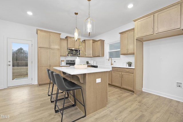 kitchen with light wood-style flooring, a kitchen bar, appliances with stainless steel finishes, and a center island