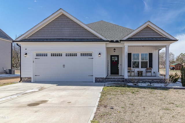 view of front facade with covered porch, central AC, a shingled roof, a garage, and driveway