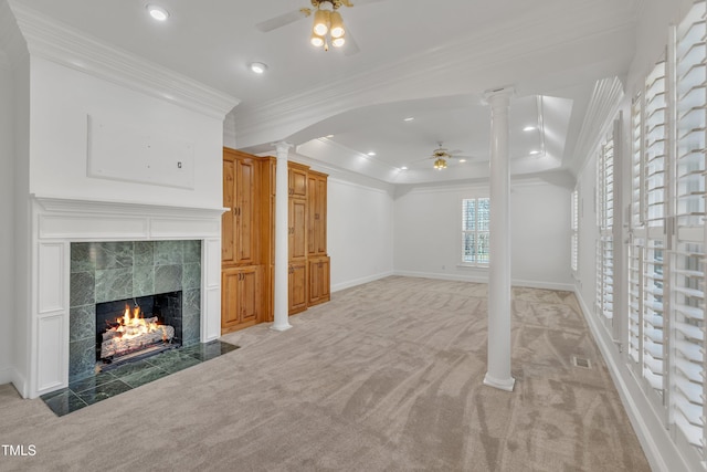 unfurnished living room featuring carpet, a tile fireplace, a ceiling fan, and ornate columns