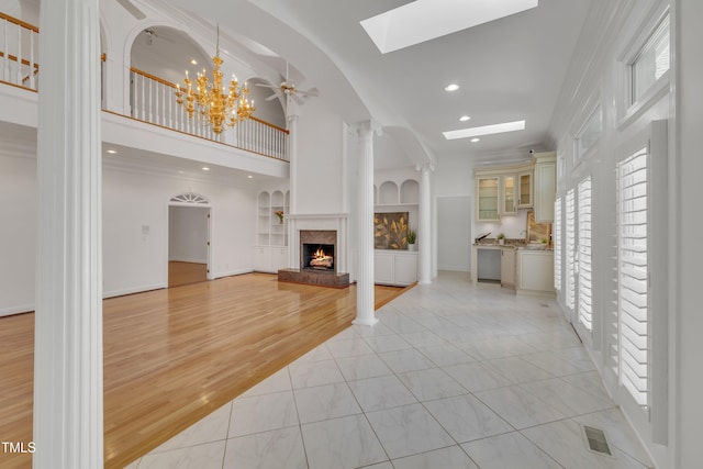 living area with built in features, recessed lighting, visible vents, light wood-type flooring, and a lit fireplace