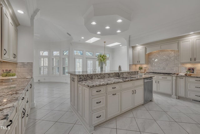 kitchen with a skylight, a center island with sink, ornamental molding, a sink, and gas cooktop