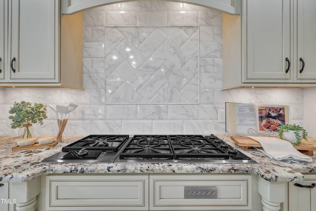 kitchen with light stone counters, decorative backsplash, and stainless steel gas stovetop