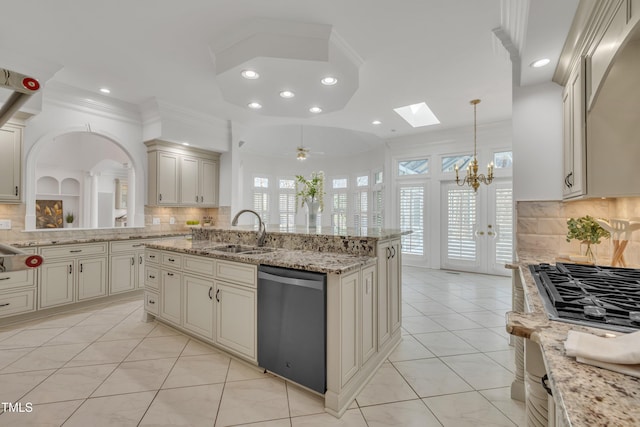 kitchen with light tile patterned floors, cream cabinets, a sink, appliances with stainless steel finishes, and backsplash