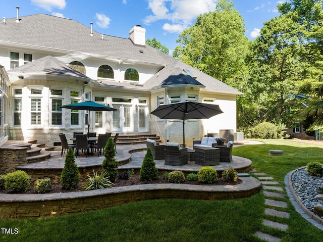 back of house featuring a shingled roof, a lawn, a patio, a chimney, and an outdoor living space