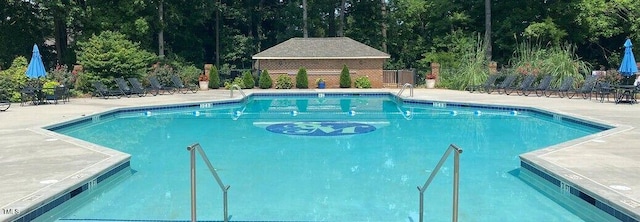 community pool with a patio area and fence