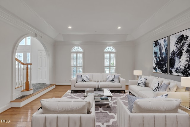 living room with light wood-type flooring, arched walkways, a healthy amount of sunlight, and ornamental molding