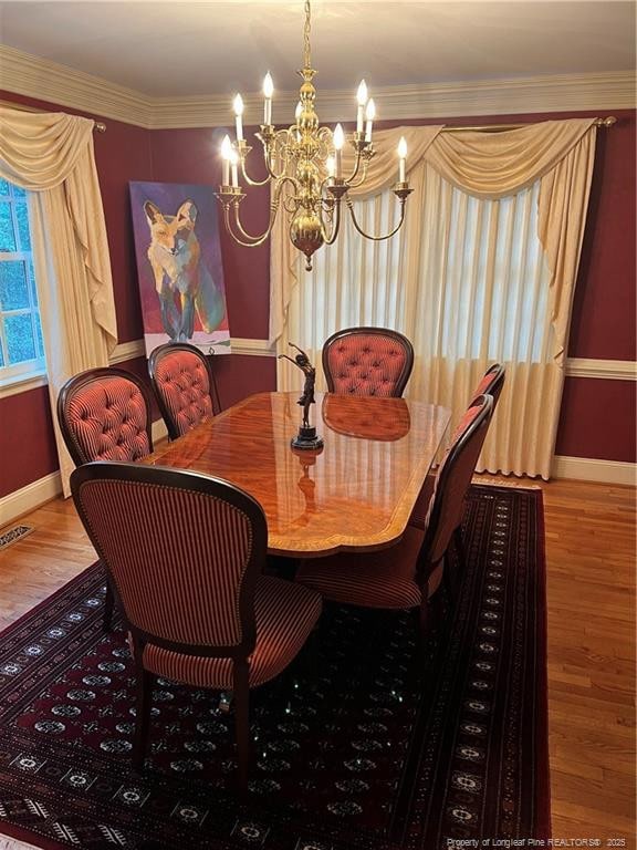 dining space with baseboards, crown molding, wood finished floors, and an inviting chandelier