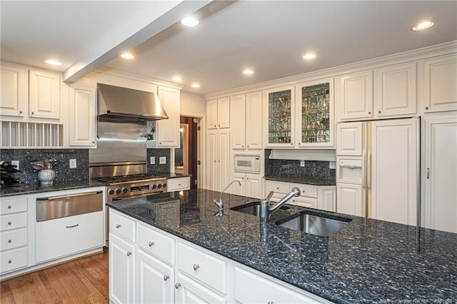 kitchen featuring wall chimney exhaust hood, dark wood-style flooring, built in appliances, a sink, and a warming drawer