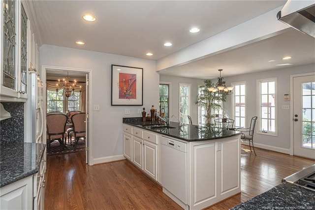 kitchen with dark wood-style floors, a peninsula, white dishwasher, and a notable chandelier