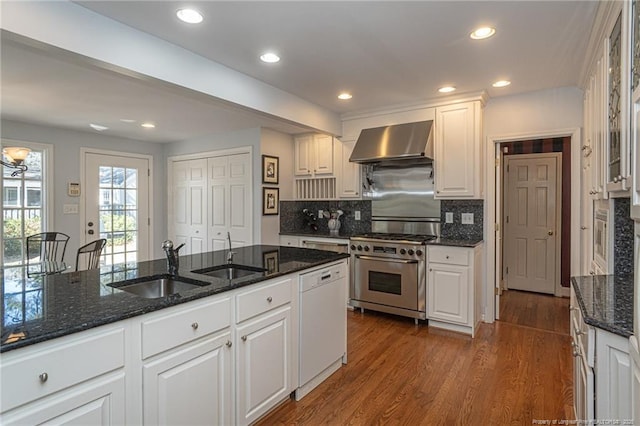 kitchen featuring dark wood-style floors, stainless steel range, wall chimney range hood, and a sink