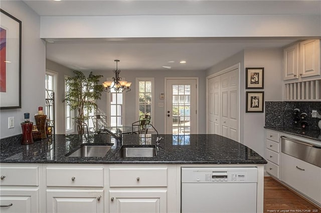 kitchen featuring dark wood finished floors, a warming drawer, a sink, dark stone counters, and dishwasher