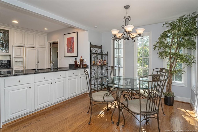 dining space with light wood-type flooring, an inviting chandelier, baseboards, and recessed lighting