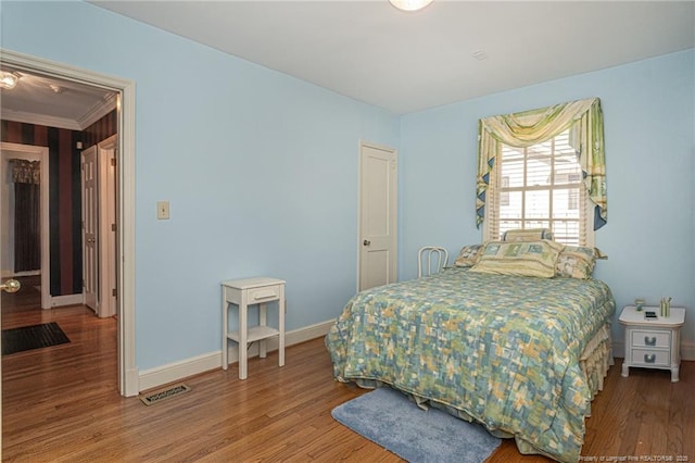 bedroom with wood finished floors, visible vents, and baseboards