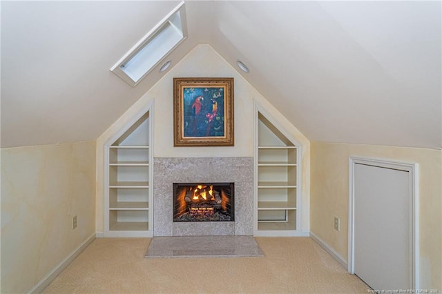 unfurnished living room featuring a warm lit fireplace, built in shelves, and vaulted ceiling