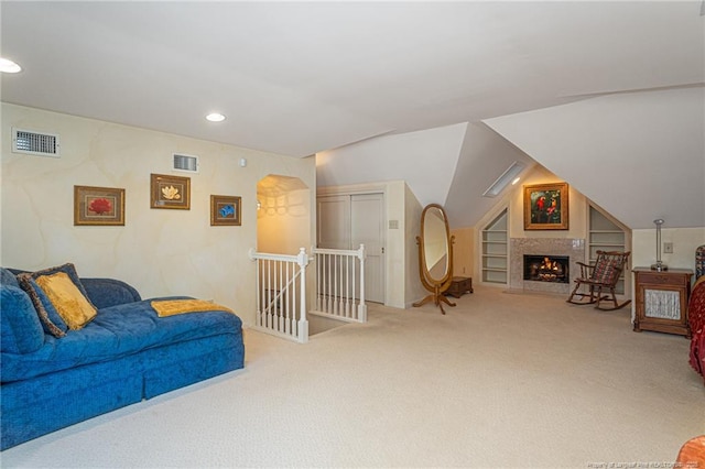 interior space with visible vents, lofted ceiling, a fireplace with flush hearth, built in shelves, and recessed lighting