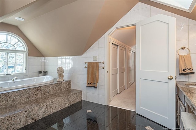 bathroom featuring tile walls, granite finish floor, vaulted ceiling, vanity, and a bath