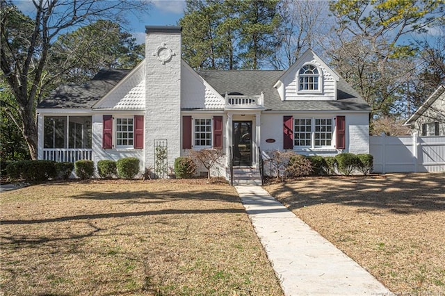 view of front of home featuring a front lawn, a chimney, a shingled roof, and fence