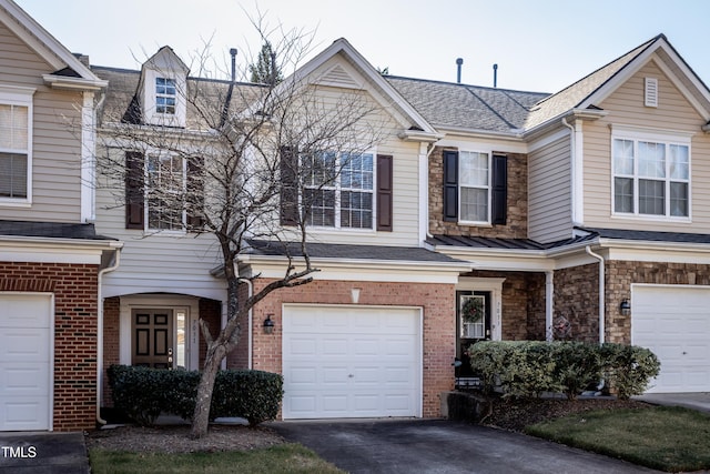 view of property featuring aphalt driveway, an attached garage, brick siding, and roof with shingles