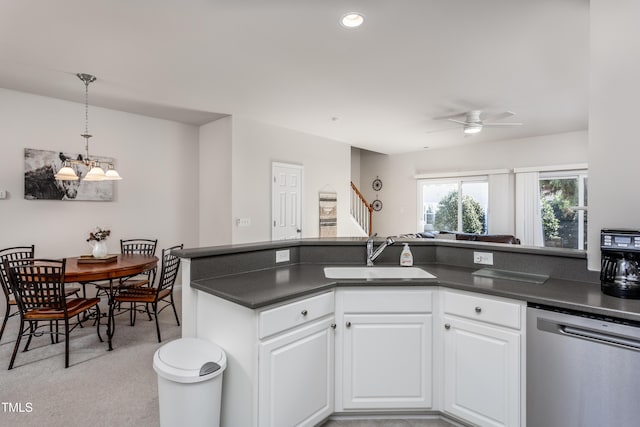 kitchen featuring white cabinetry, a sink, dishwasher, dark countertops, and ceiling fan with notable chandelier