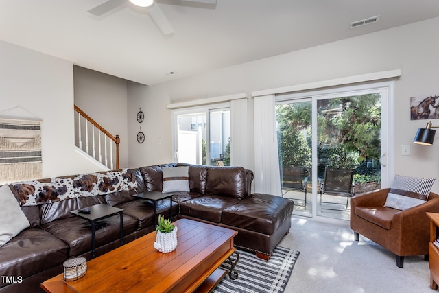 living area featuring stairway, carpet flooring, a ceiling fan, and visible vents