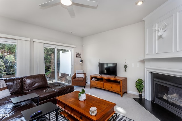 carpeted living area featuring a fireplace, baseboards, and ceiling fan