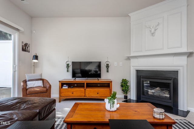 living area with baseboards, carpet floors, plenty of natural light, and a fireplace with flush hearth